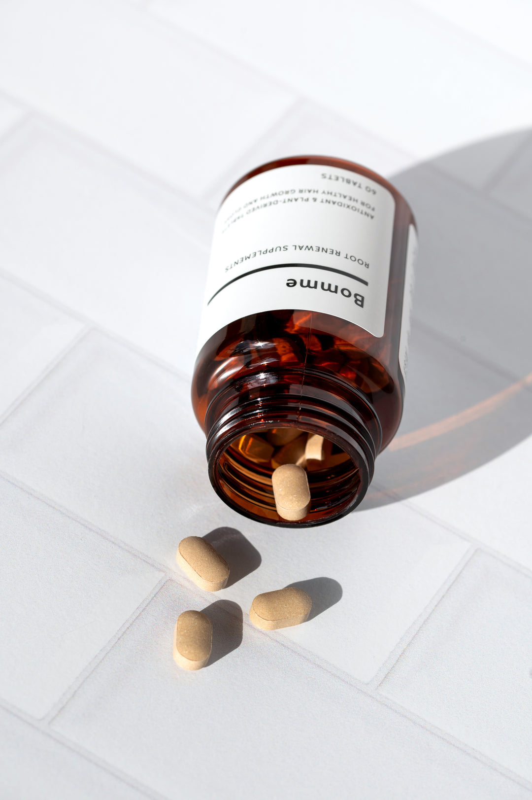 Bomme Root Renewal hair growth supplement—plant-based tablets for healthy scalp and hair, shown in amber bottle on white background